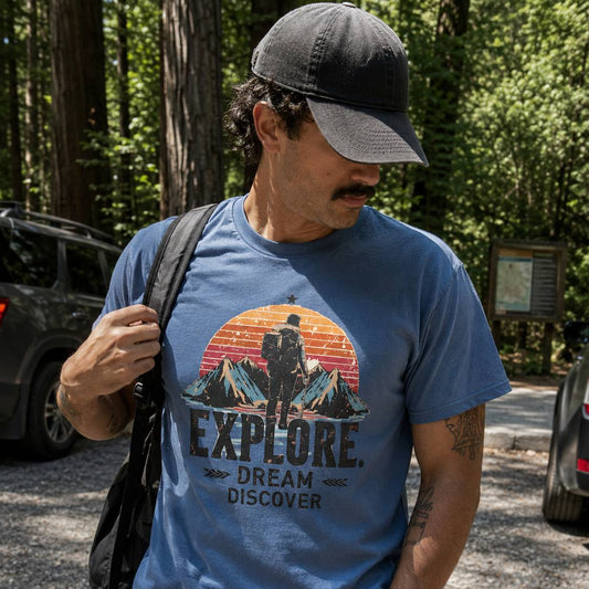 Man wearing a blue t-shirt with an 'Explore' graphic in a forest setting