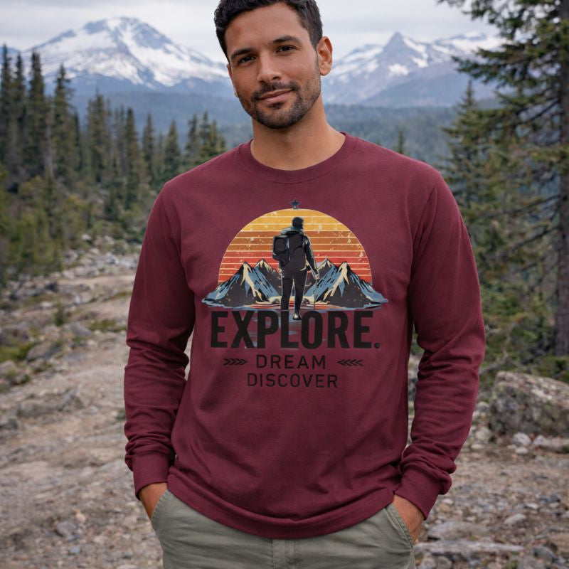 Man wearing a maroon long-sleeve shirt with outdoor design and text in a mountainous landscape.