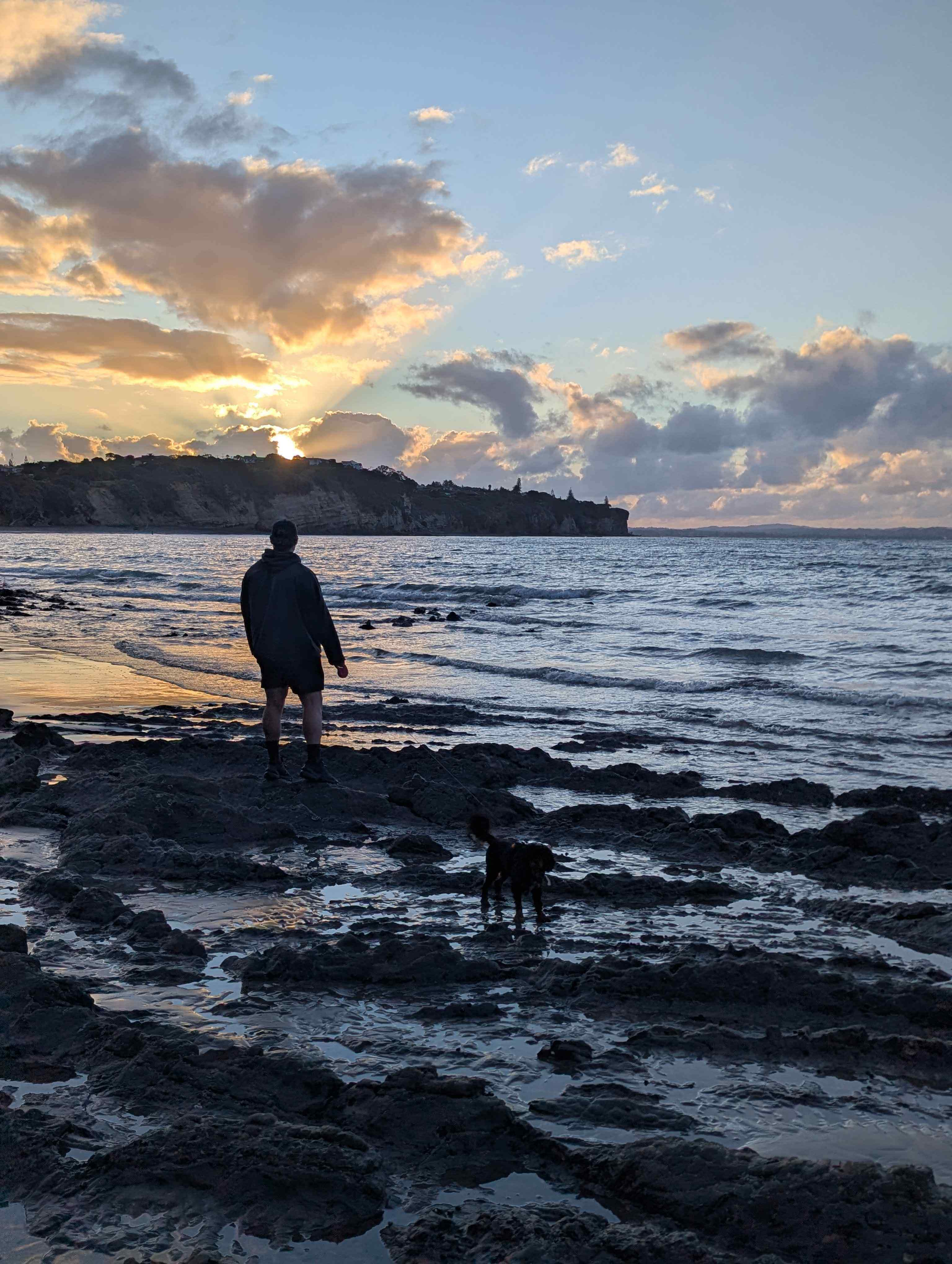 Chris and Mellow standing on a beach at sunset wearing a Wyld Peak hoodie, relaxed outdoor lifestyle moment by the ocean
