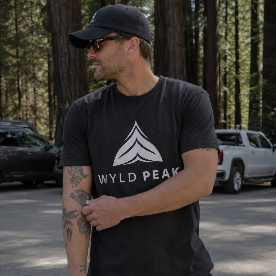 Man wearing a black t-shirt with 'Wyld Peak' logo in a forest setting