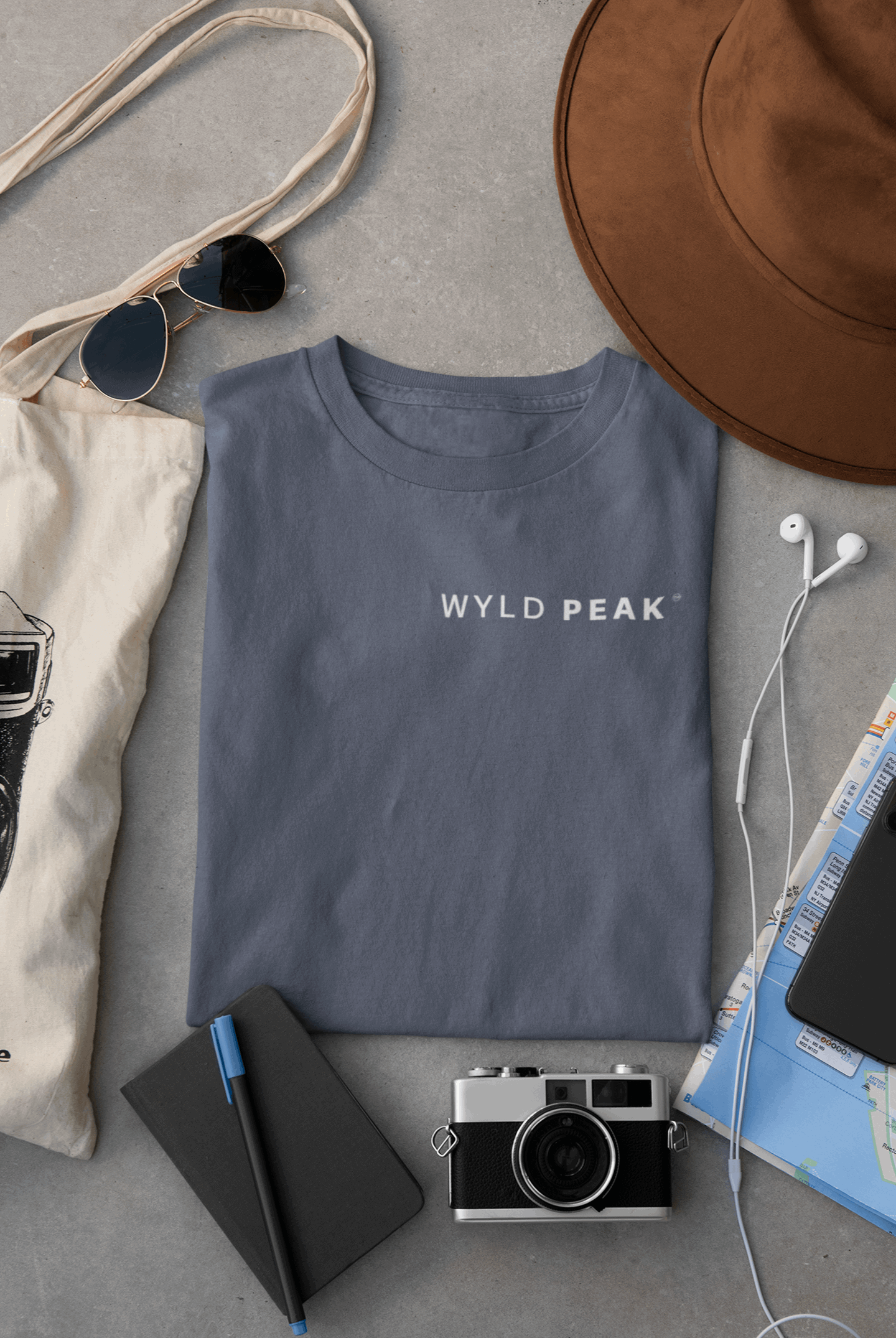 Wyld Peak men’s signature tee in indigo blue laid flat on desk.