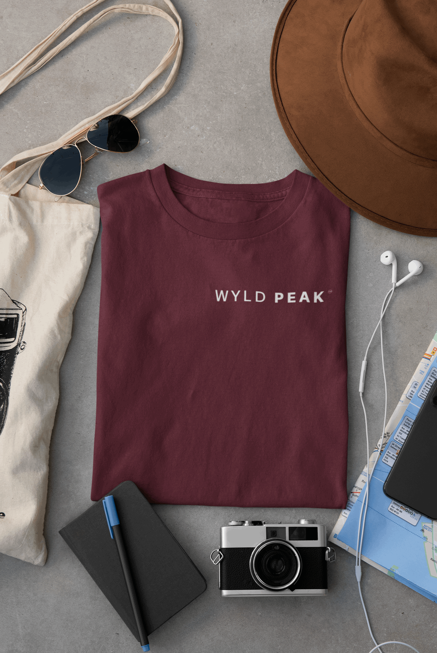 Wyld Peak men’s signature tee in maroon laid flat on desk.