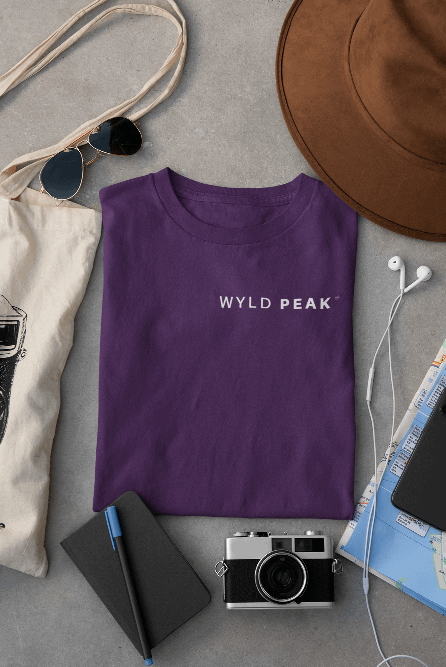 Wyld Peak men’s signature tee in purple laid flat on desk.