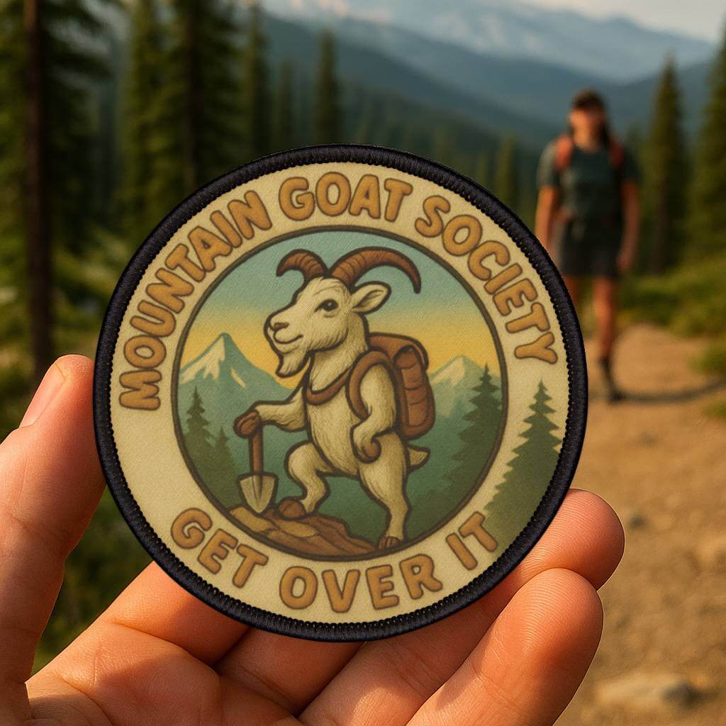 Mountain Goat Society patch held in a forest setting, alpine inspired design made for rugged outdoor gear