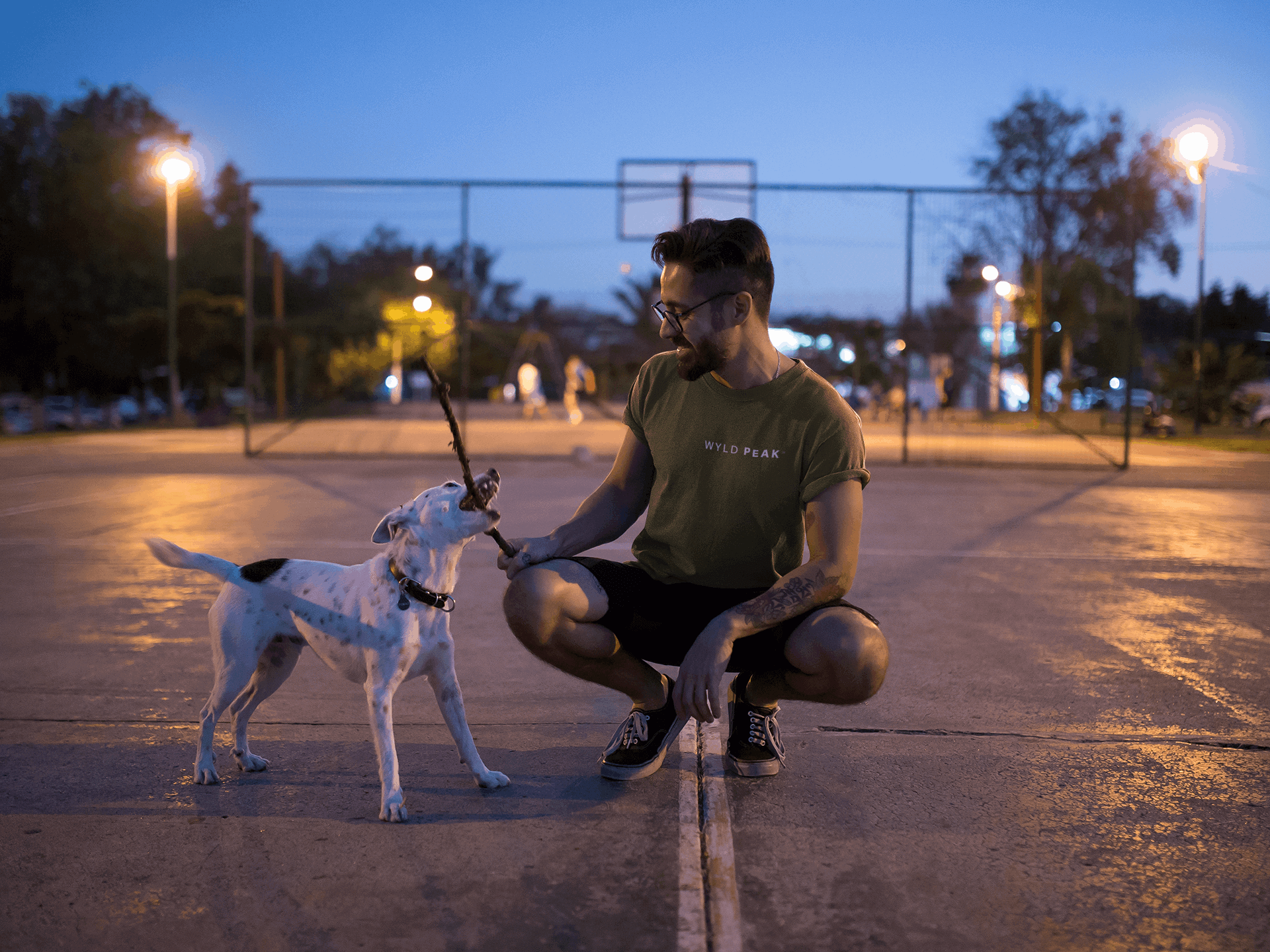 Man playing with dog in Fresno wearing Wyld Peak Signature tee in military green.