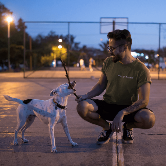 Man playing with dog in Fresno wearing Wyld Peak Signature tee in military green.