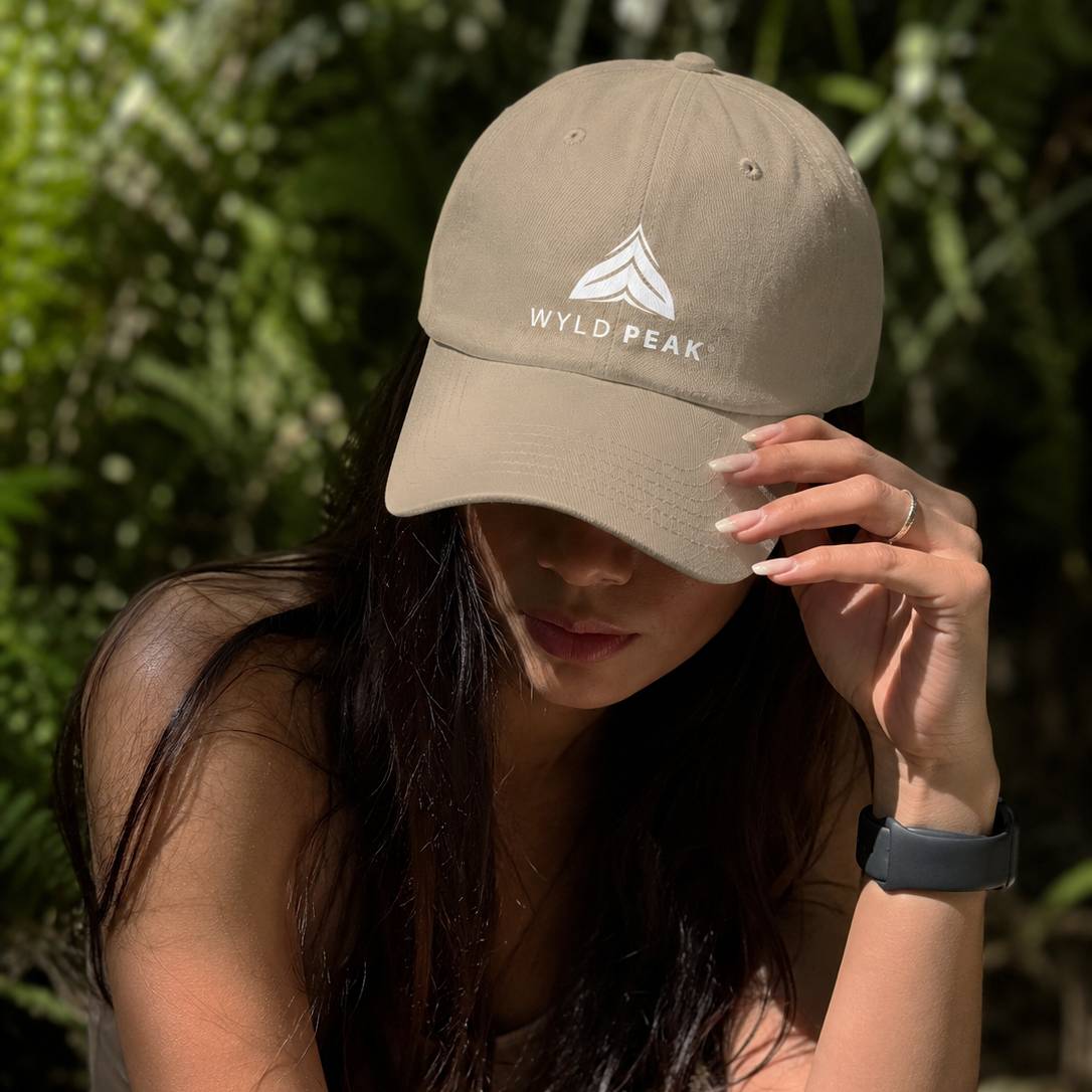 Person wearing a beige cap with 'Wyld Peak' logo against a green background