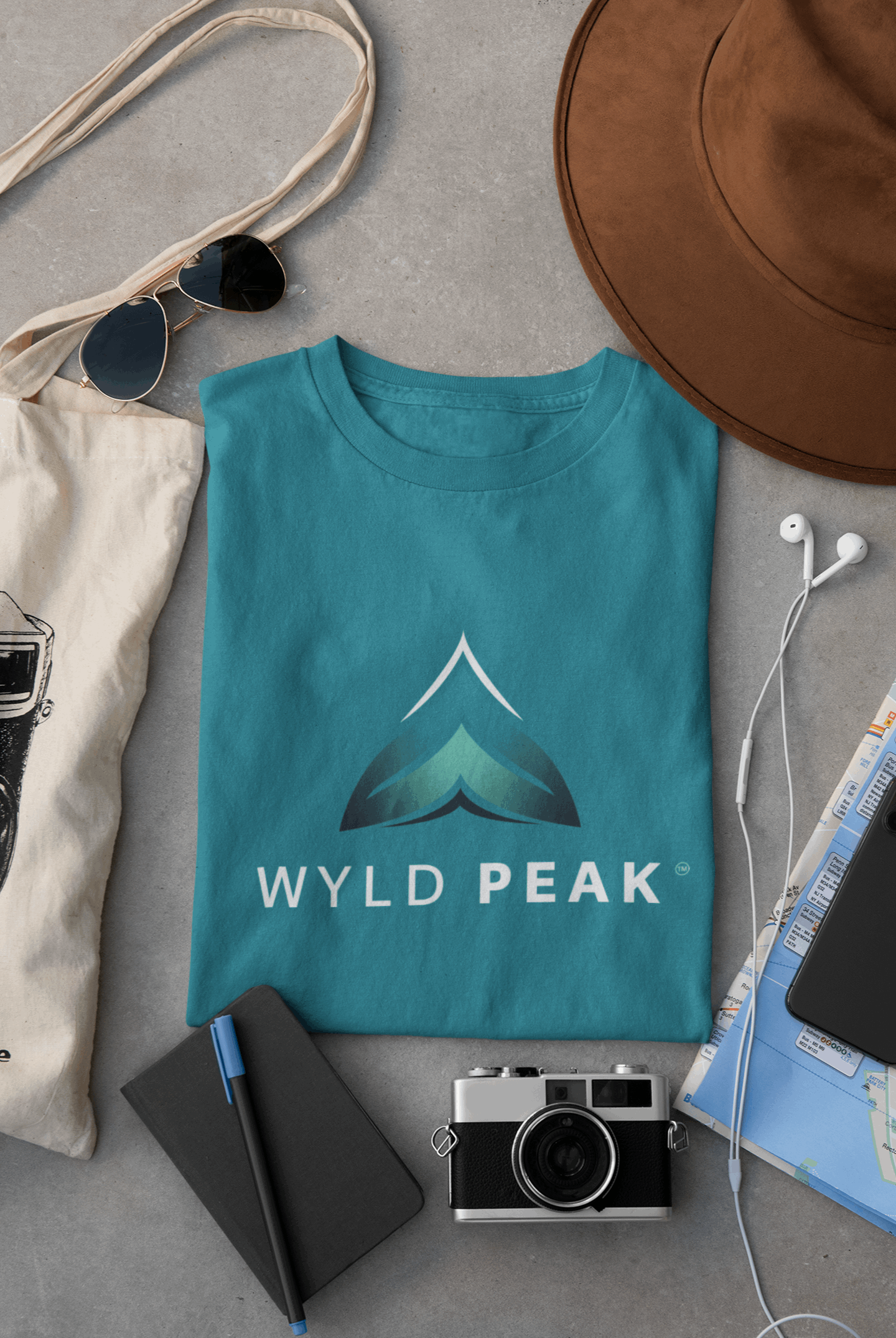 Galapagos blue Wyld Peak women’s branded tee laid flat on desk.