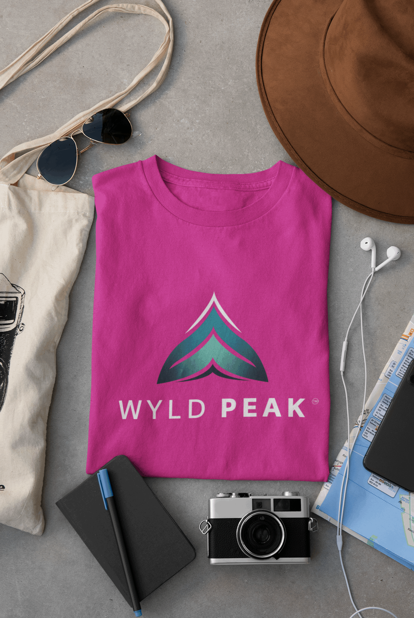 Pink Wyld Peak women’s branded tee laid flat on desk.