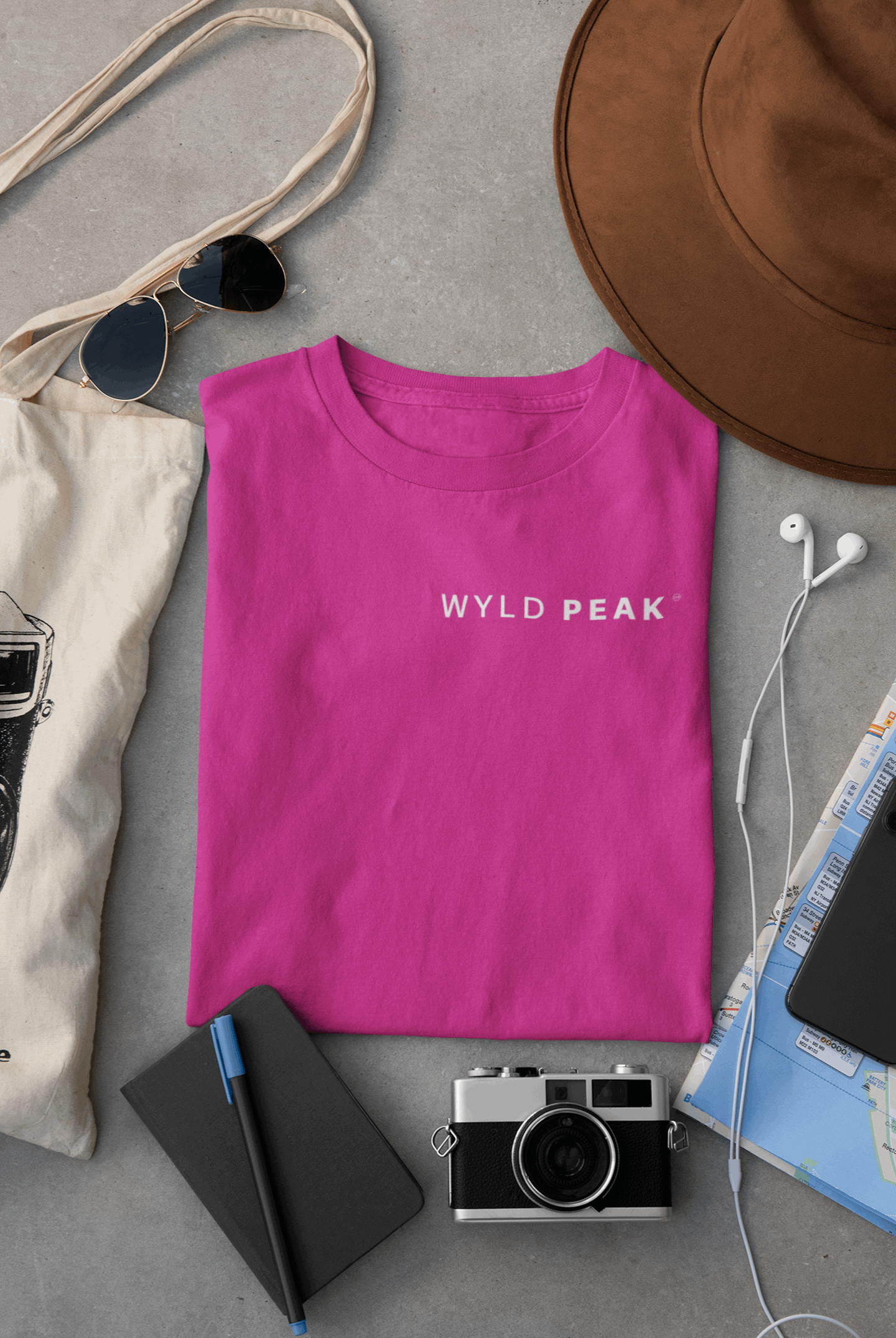 Wyld Peak women’s signature tee in pink laid flat on desk.