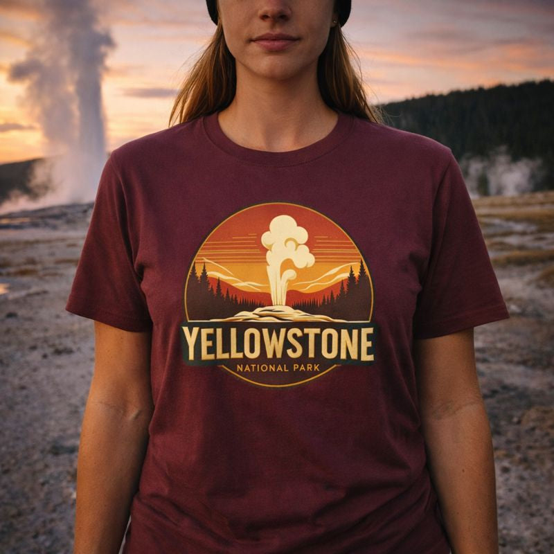 Person wearing a maroon t-shirt with Yellowstone National Park graphic in front of a geyser at sunset.