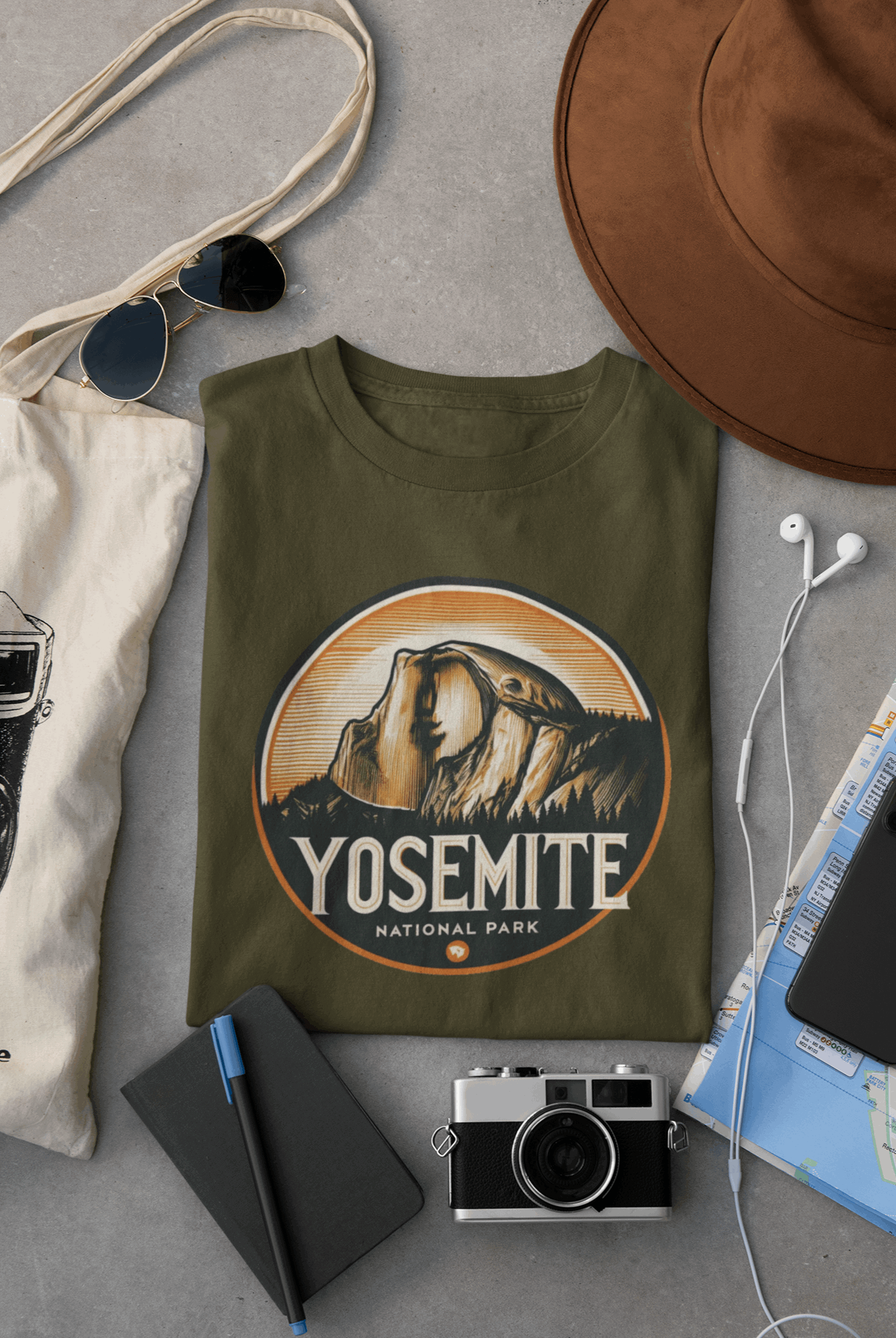 Wyld Peak Yosemite Half Dome organic cotton tee in military green laid flat on desk.