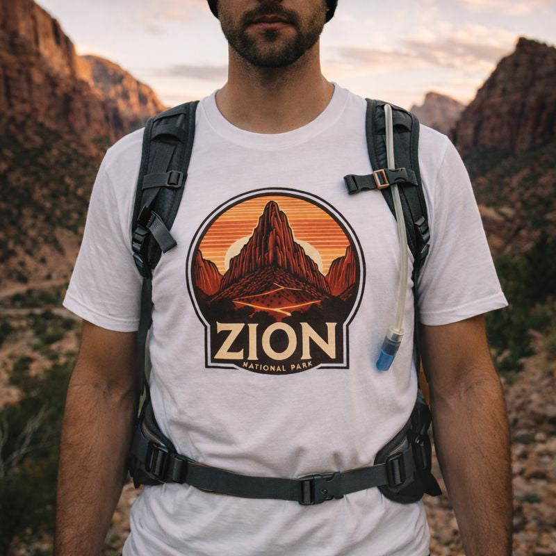 Person wearing a white t-shirt with Zion National Park graphic in a mountainous landscape.