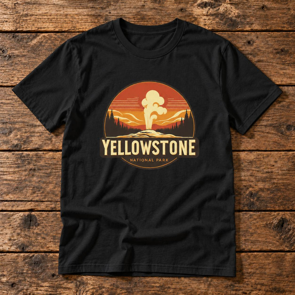 A black short-sleeve t-shirt laid flat on a rustic wooden plank background, featuring a circular Yellowstone National Park graphic on the chest with a sunset gradient, mountains, trees, and the text 'YELLOWSTONE NATIONAL PARK'.