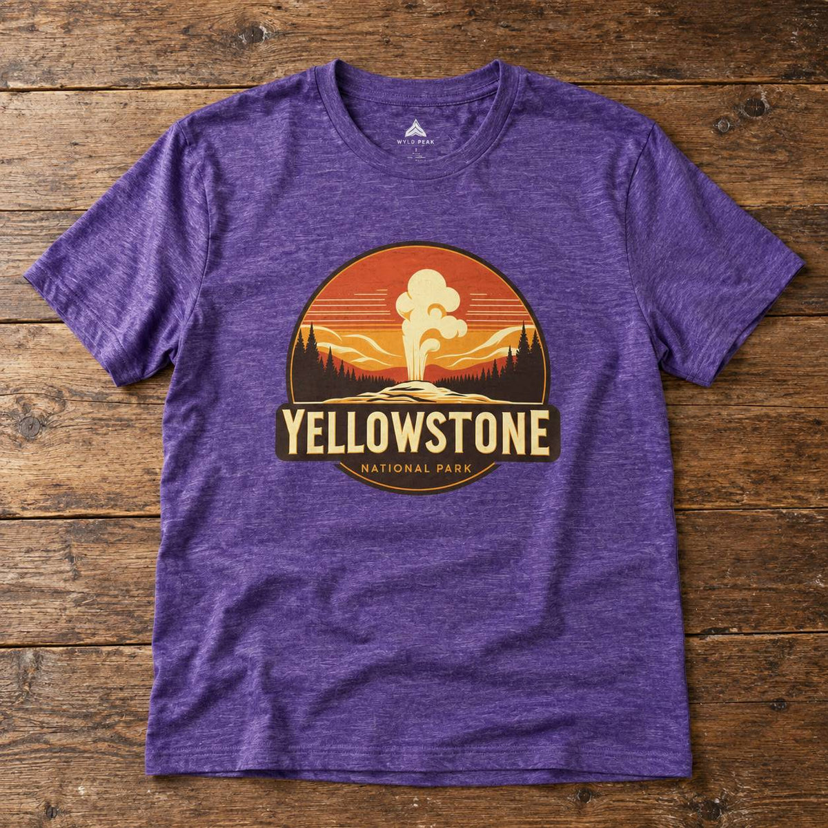 A heather purple short-sleeve t-shirt with a circular Yellowstone National Park graphic on the chest, laid flat on a rustic wooden background.
