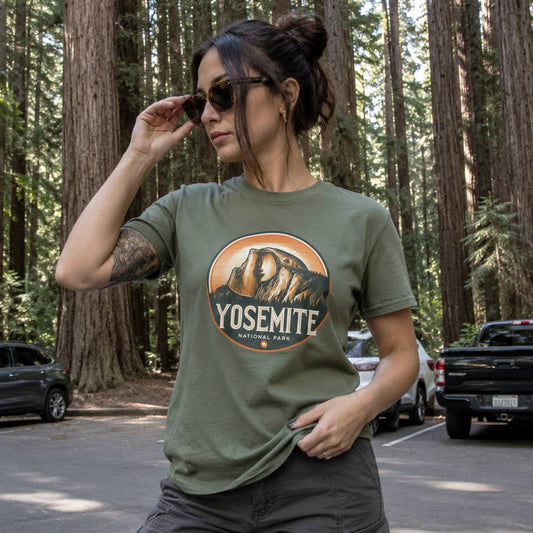 Woman wearing a green Yosemite National Park t-shirt in a forest setting.
