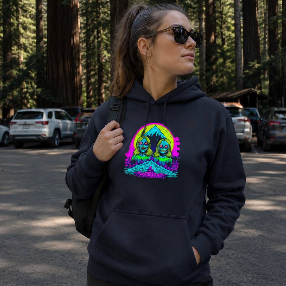 Person wearing a black hoodie with a colorful graphic design in a forest setting