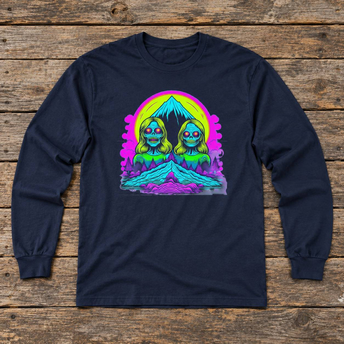 A navy blue long-sleeve t-shirt with a colorful graphic print of two stylized green and blue figures in front of a mountain under a neon rainbow sky, laid flat on a rustic wooden plank background.