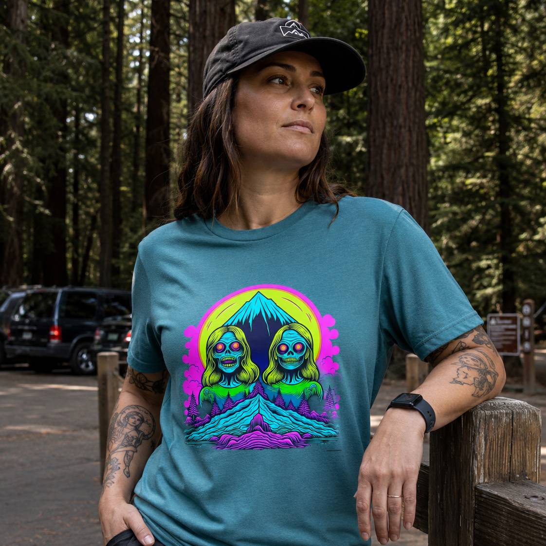 Person wearing a teal t-shirt with a colorful graphic design in a forest setting