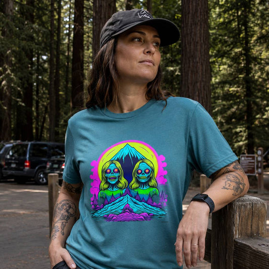 Person wearing a teal t-shirt with a colorful graphic design in a forest setting