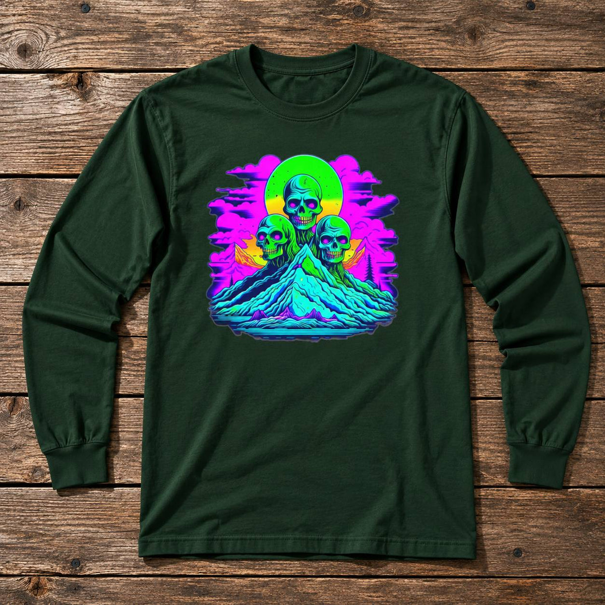 A dark forest green long-sleeve t-shirt with a vibrant, colorful graphic print on the chest, laid flat on a rustic wooden plank background.