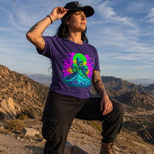 Person wearing a purple t-shirt with a colorful graphic design in a desert landscape